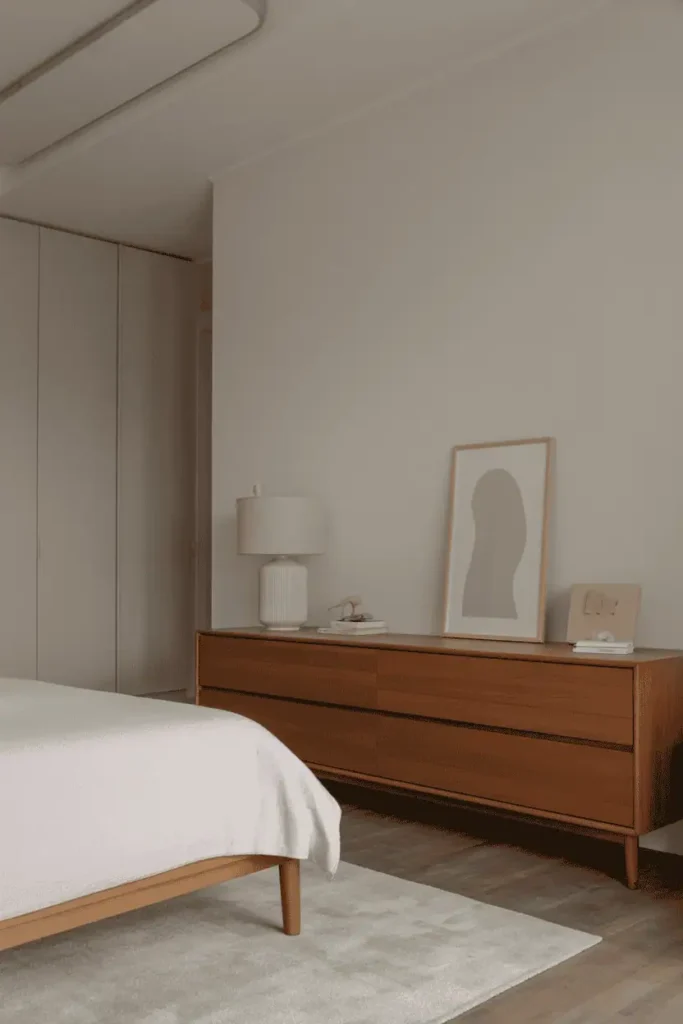 Bedroom with low wooden dresser and closed storage, flat fronts, minimal styling, neutral colors, calm and uncluttered atmosphere, realistic interior photography, no people, no text, no watermark