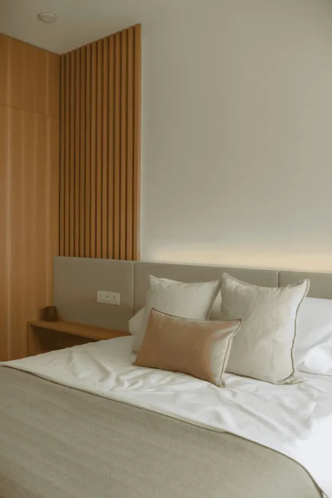 Bedroom with wooden bench placed at the foot of the bed, simple form, warm wood tone, neutral bedding, calm and balanced layout, realistic interior photography, no people, no text, no watermark